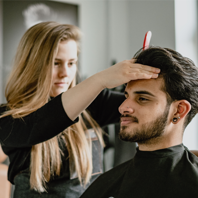 A woman cutting a man's hair in a salon